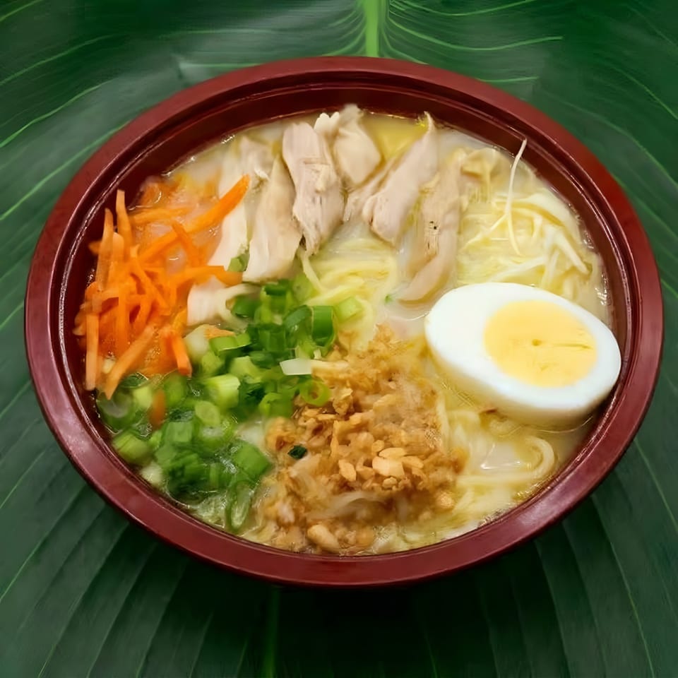 Chicken noodle soup with carrots, green onions, fried garlic, and a hard-boiled egg.